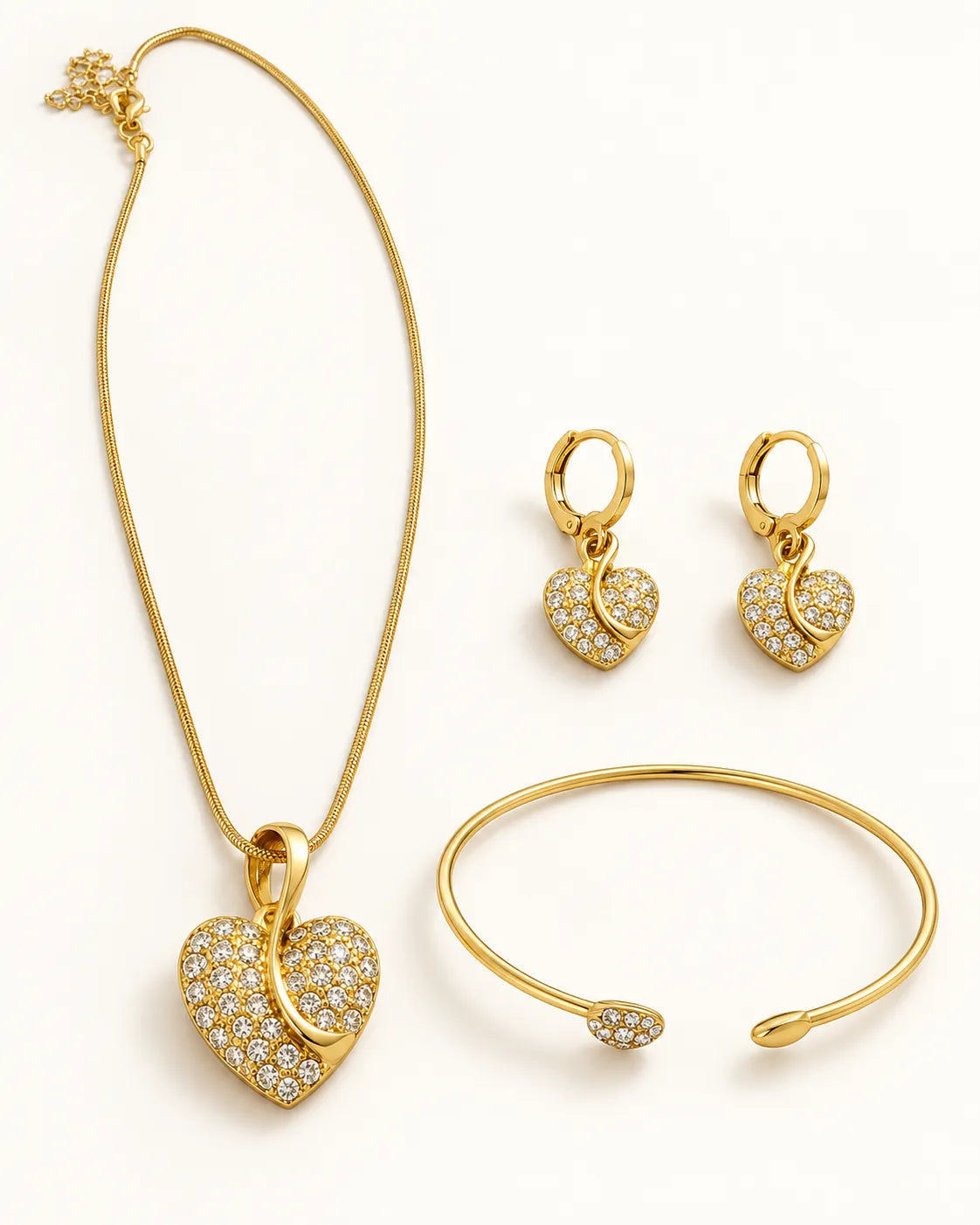 Three-piece gold pavé heart jewellery set laid out on white