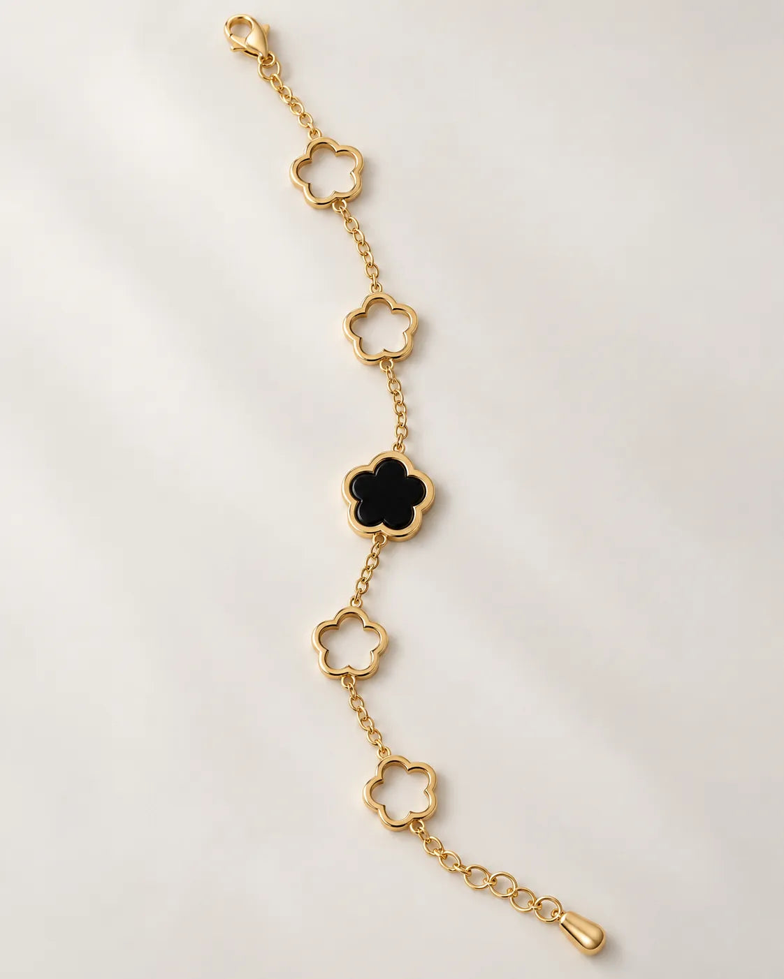 Gold and black clover chain bracelet laid straight on a white background