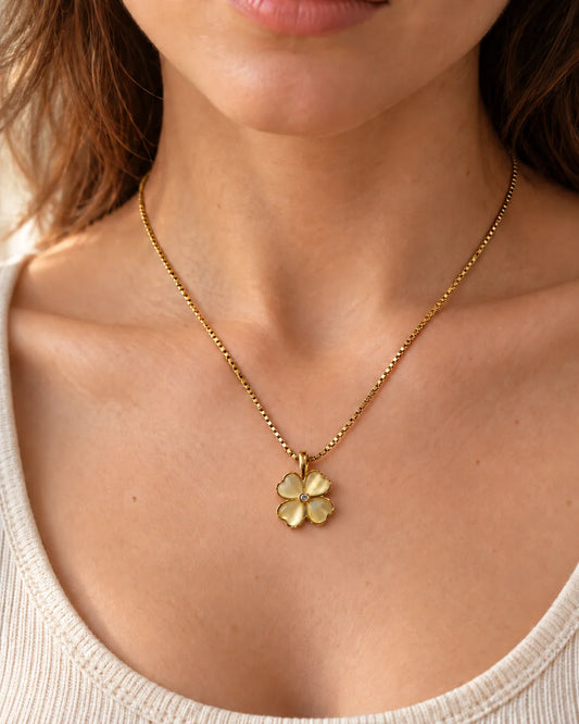 Model wearing the Primrose four-petal heart clover necklace with an ivory scoop-neck top