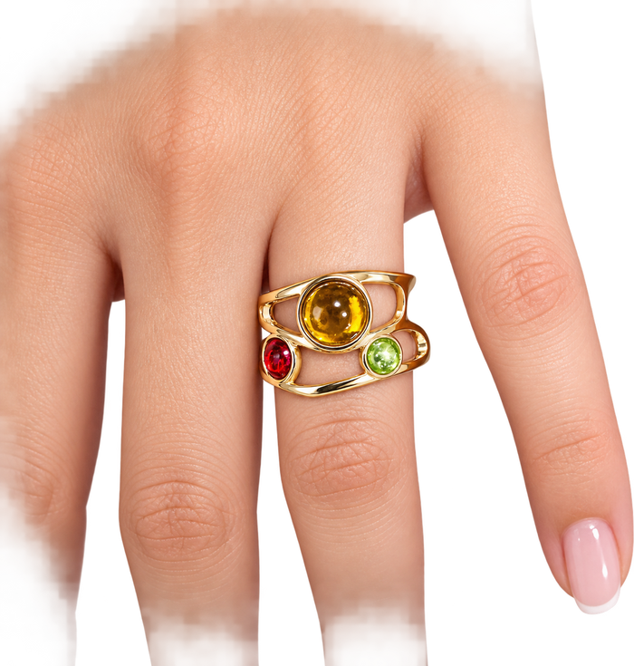 A gold ring with a central round yellow gemstone and three smaller accent gemstones in red, green, and orange, shown worn on a finger against a white background.