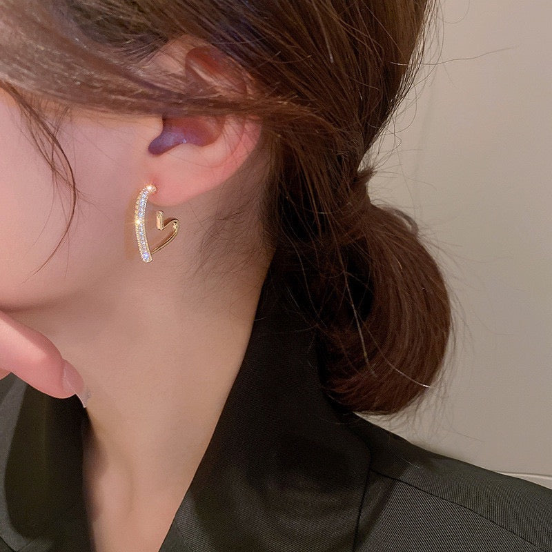 Heart-shaped earring worn by a person with a neutral background