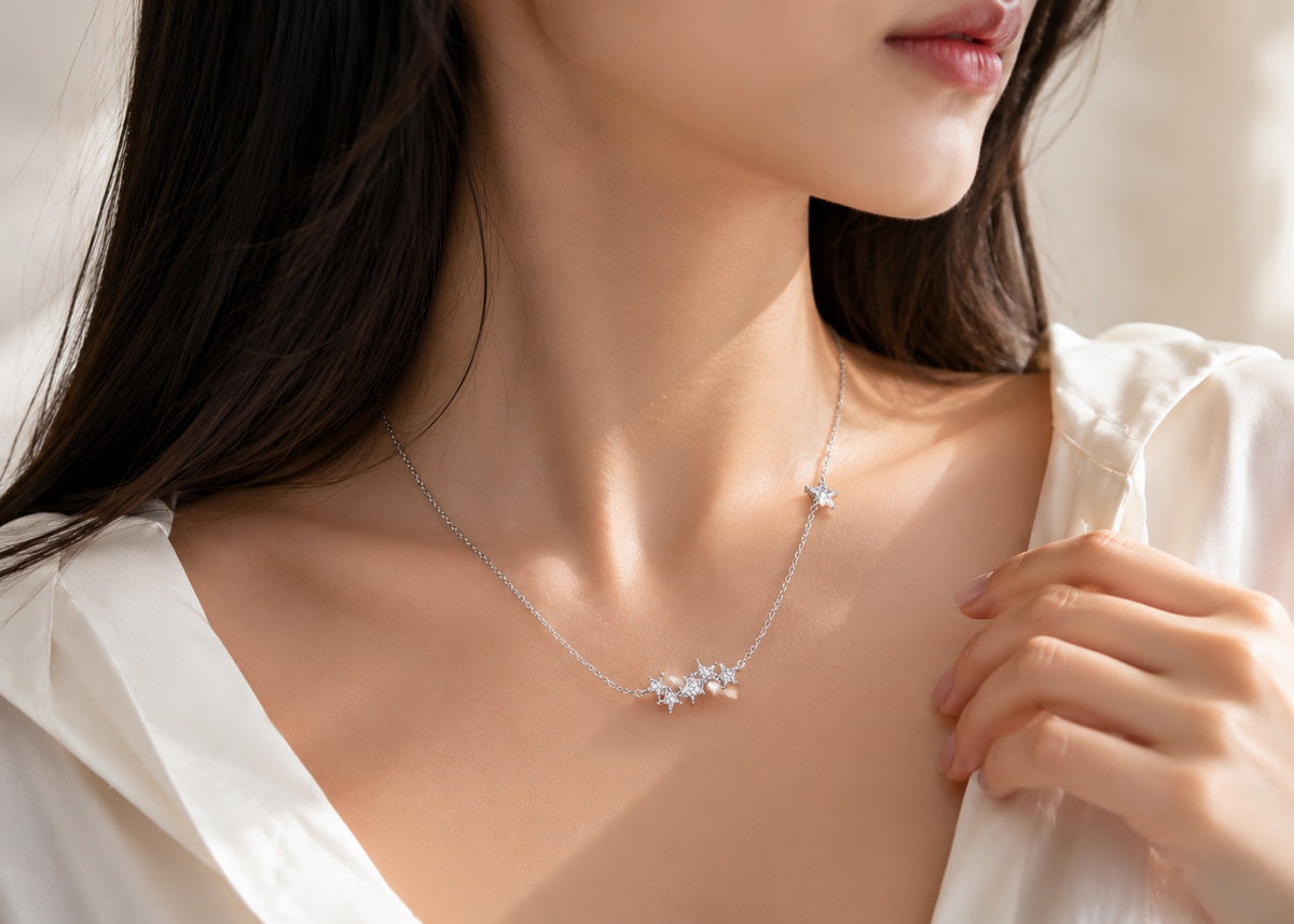 A close-up lifestyle shot of a model wearing a delicate silver necklace with a small cluster of clear crystals at the center, accented by a tiny star on the chain.
