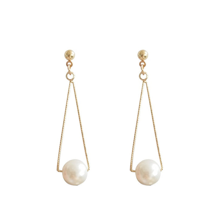 A pair of gold dangle earrings with a small gold ball stud, a thin gold wire frame, and a white pearl drop, shown on a plain white background.