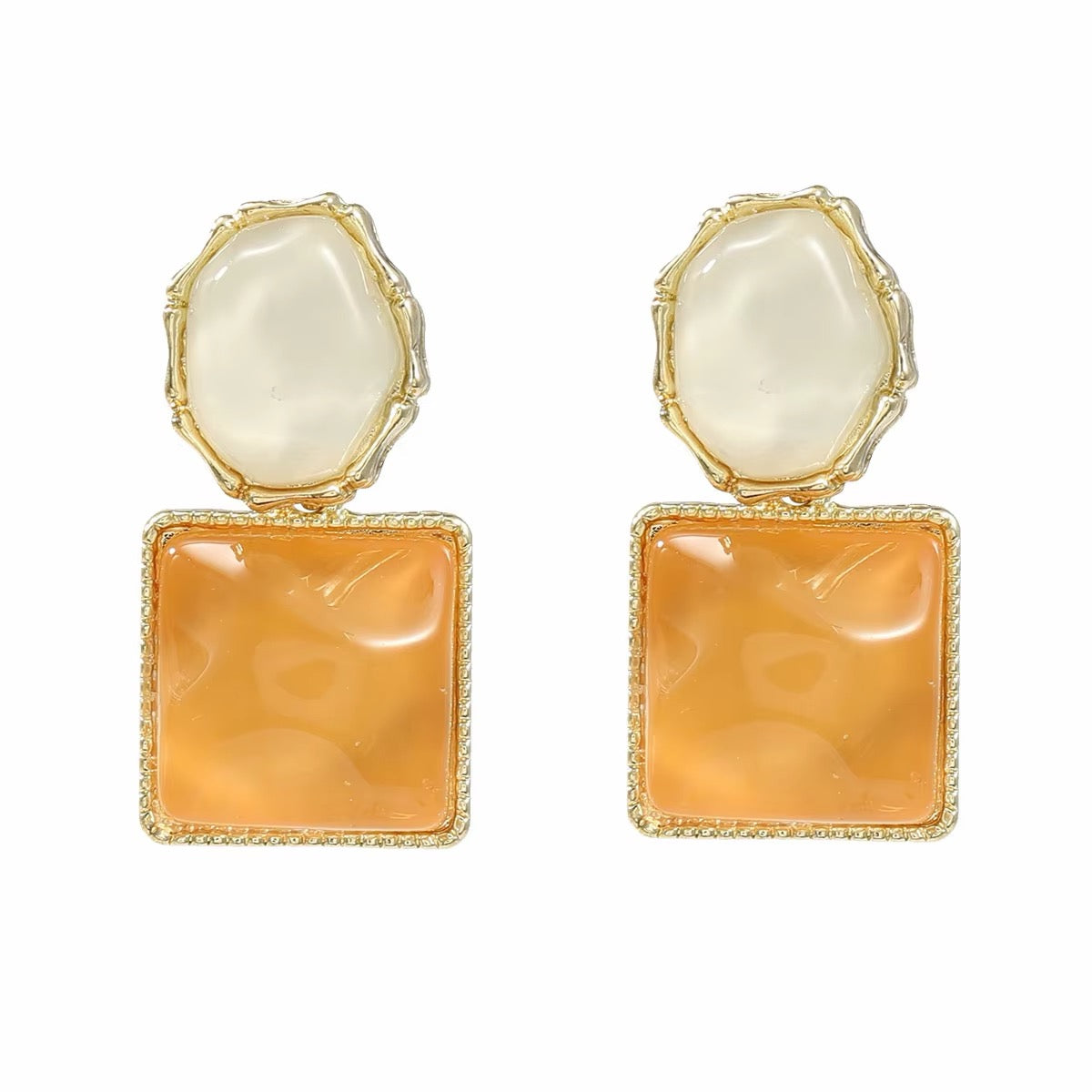 A pair of gold-tone drop earrings featuring a large, textured square orange cabochon stone on the bottom and an irregular cream-colored stone on top, set in gold bezel settings against a plain white background.