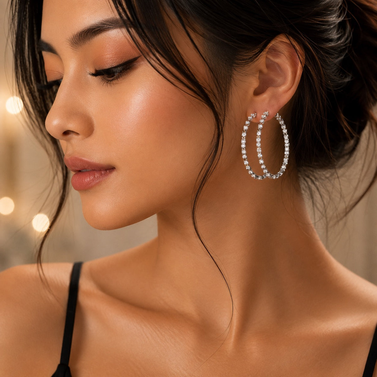 A close-up lifestyle shot of a woman wearing a pair of large silver hoop earrings adorned with sparkling clear stones.