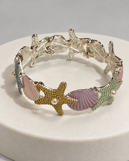 Marina pastel enamel starfish and shell bracelet in silver tone on a white stone plinth