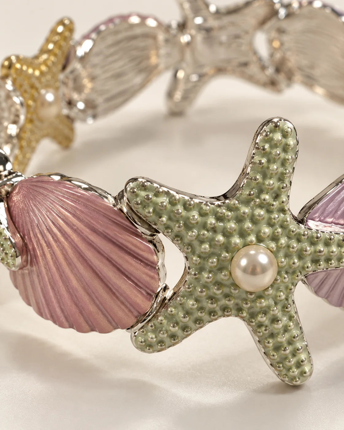 Close-up of lilac enamel shell and sage green starfish with pearl-look centre