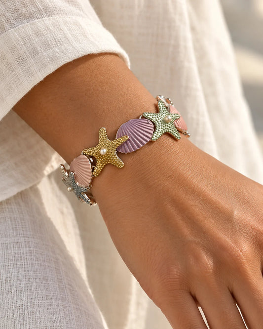 Pastel starfish and shell bracelet worn on the wrist with a linen shirt
