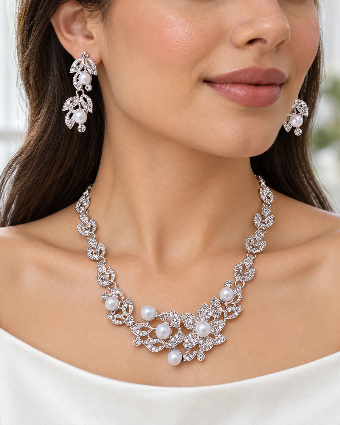 Woman wearing the Ivy silver leaf and pearl bridal necklace and earrings with an ivory top