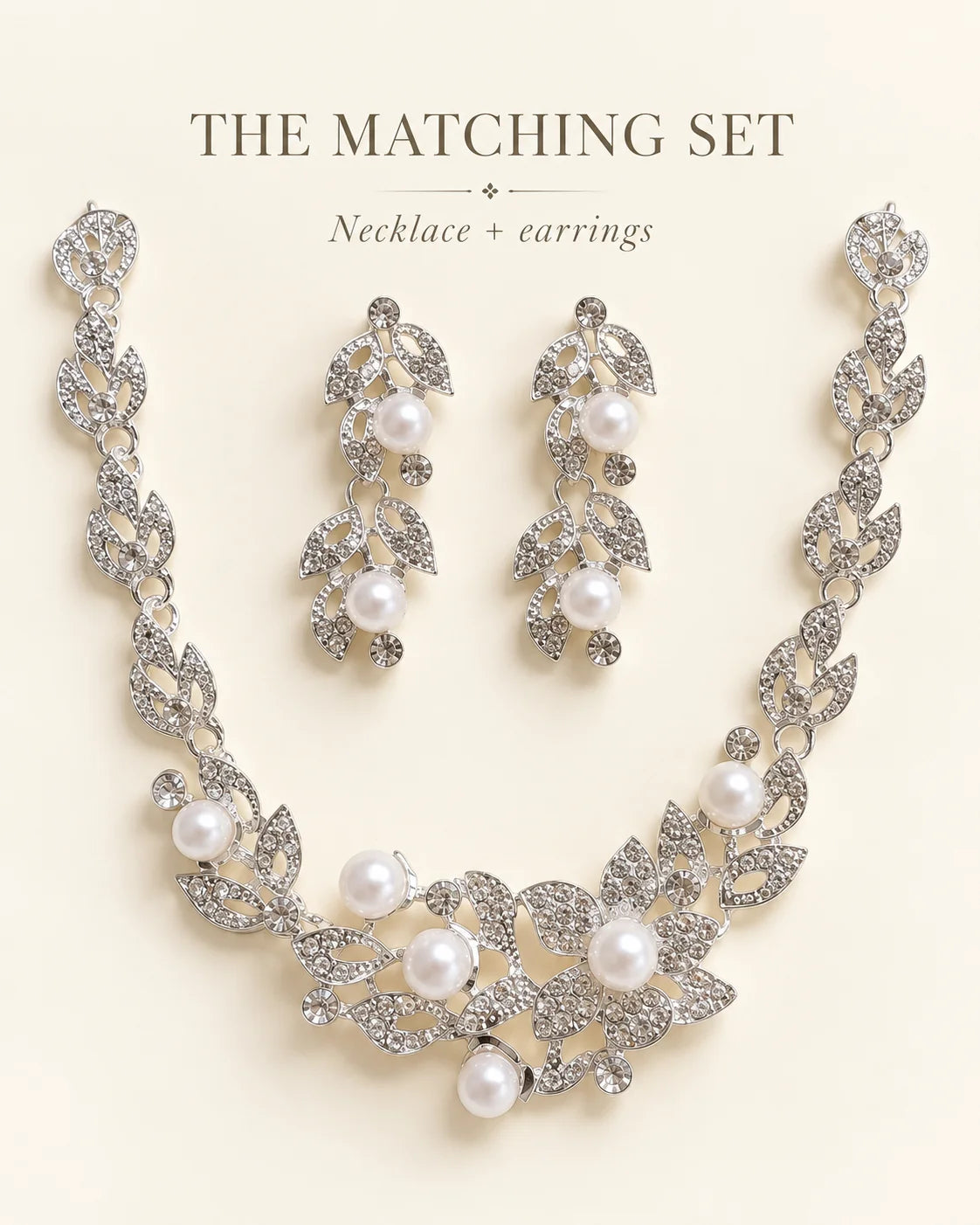 The matching set: Ivy silver leaf necklace and pearl drop earrings on a cream background