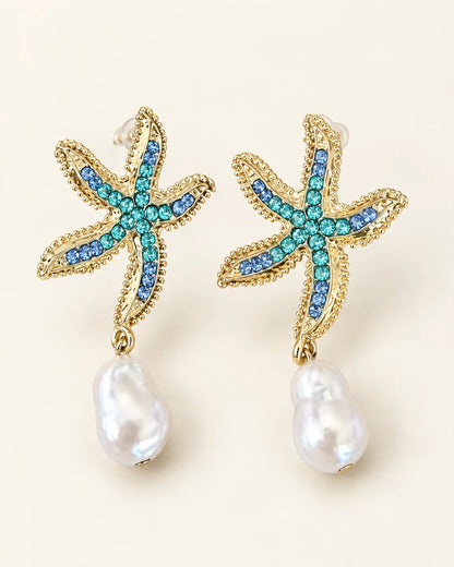 Gold starfish stud earrings with turquoise stones and pearl-look drops on a cream background