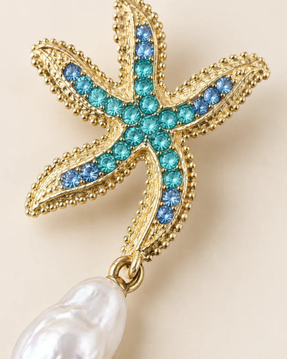 Close-up of the textured gold starfish, blue stones and baroque-style pearl-look drop