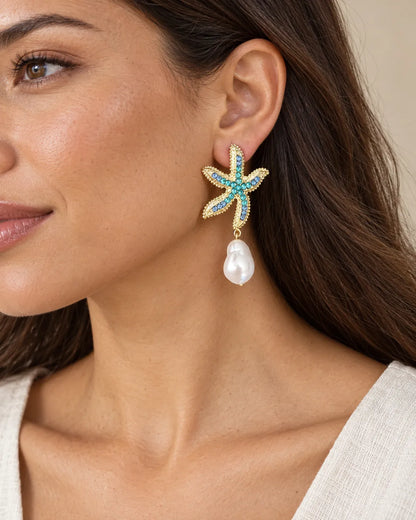 Close-up of a model wearing the gold starfish pearl drop earring