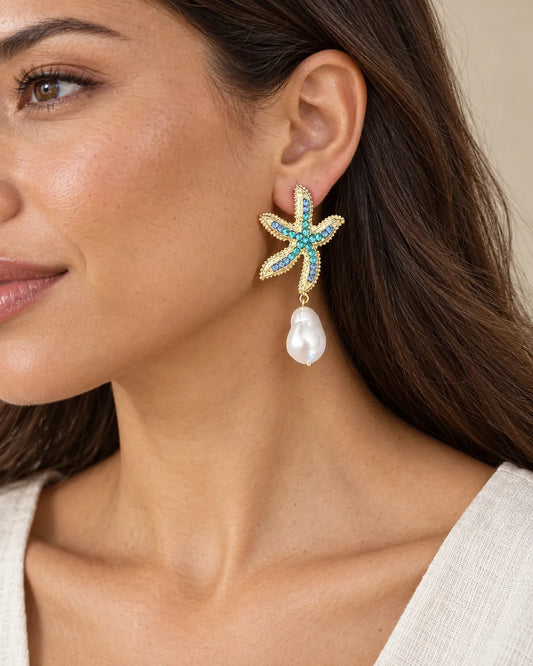 Close-up of a model wearing the gold starfish pearl drop earring