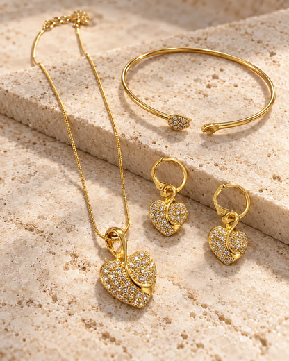 Gold pavé heart necklace, huggie earrings and cuff bangle on a stone block