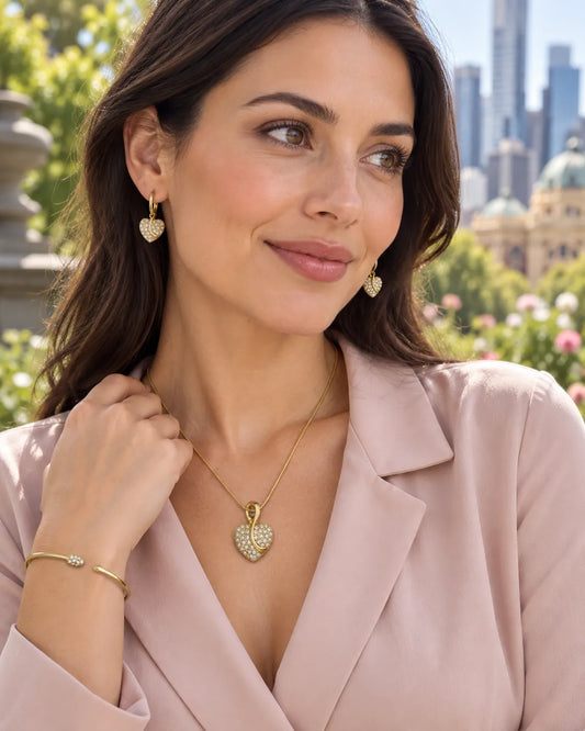 Model in a blush blazer wearing the gold pavé heart necklace and bangle