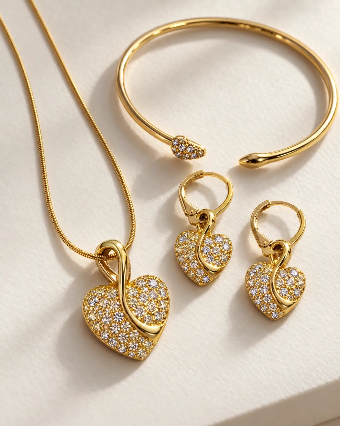 Close-up of the gold pavé heart pendant, heart drop earrings and cuff
