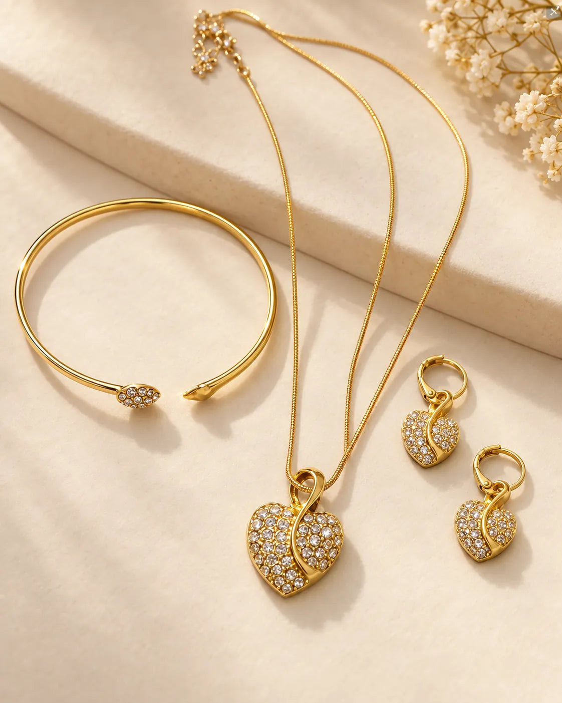 Gold heart set with snake chain necklace, earrings and cuff on linen