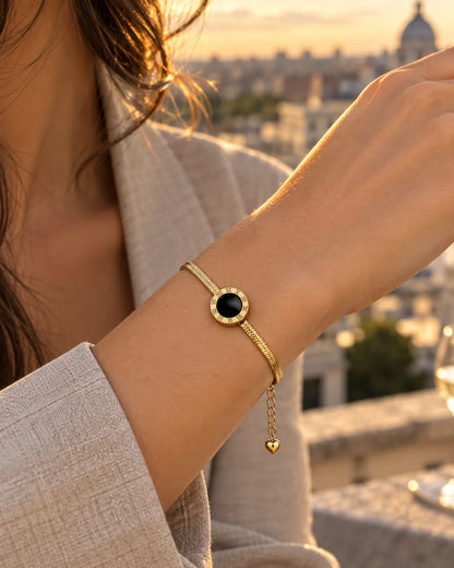 Wrist wearing the gold Roman numeral bracelet at sunset