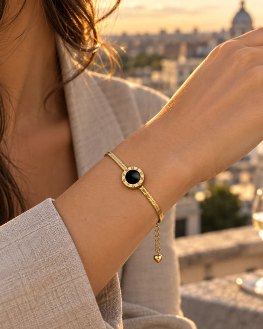 Wrist wearing the gold Roman numeral bracelet at sunset