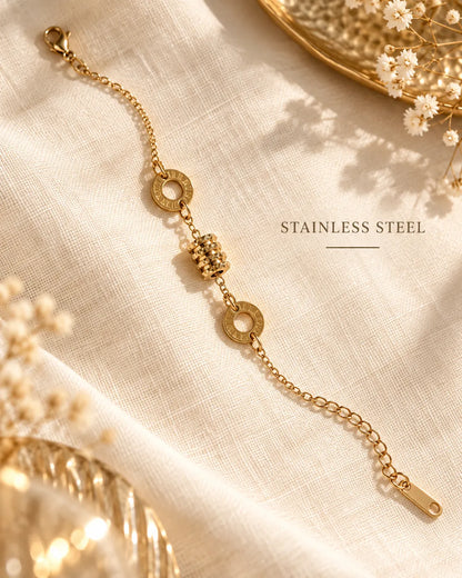 Gold drum charm chain bracelet laid on linen