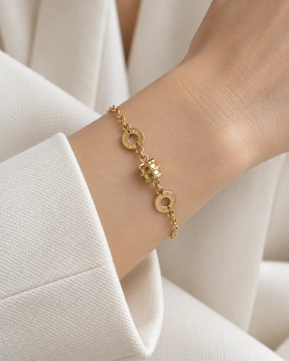 Wrist in a white sleeve wearing the gold Roman numeral bracelet