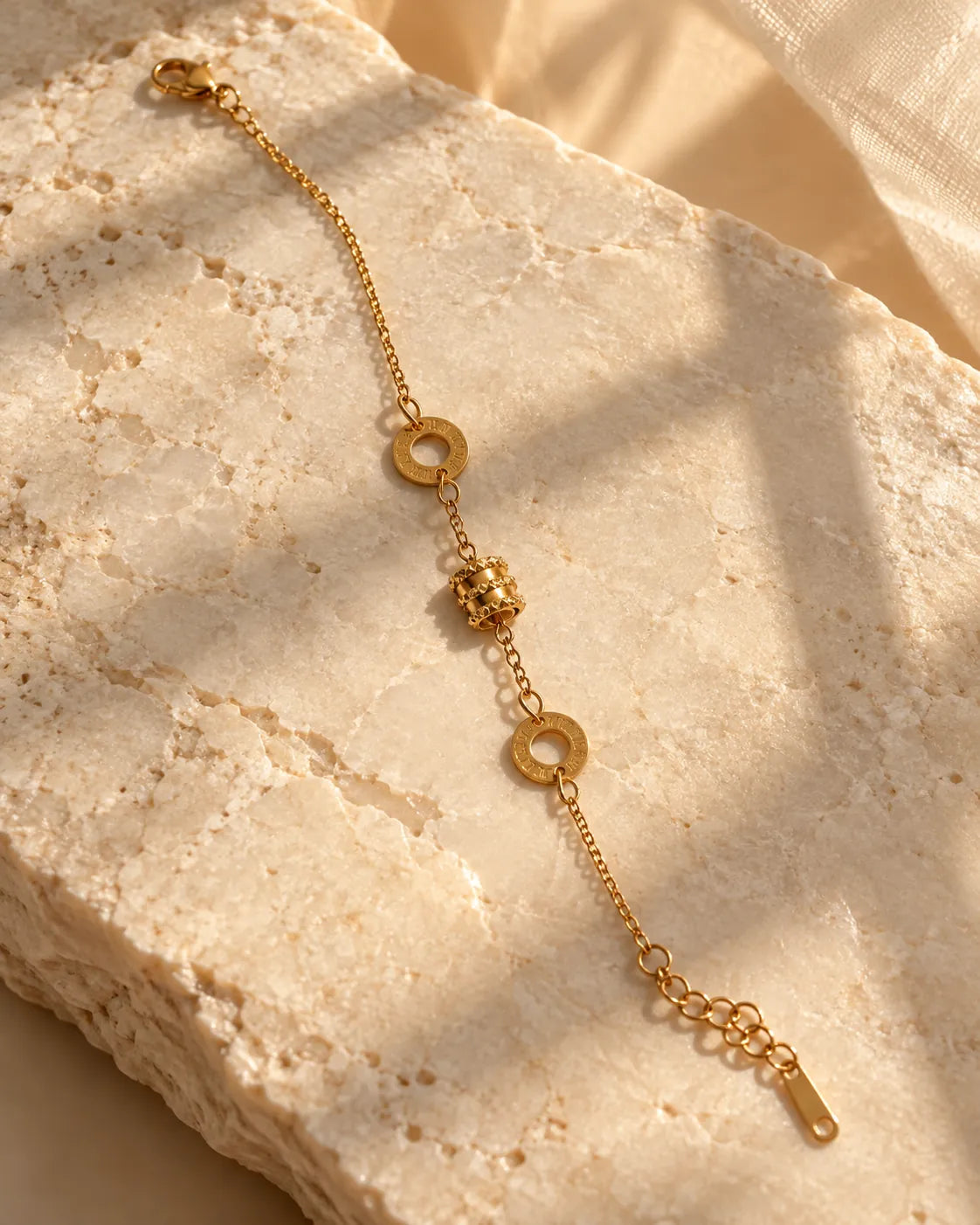 Gold Roman numeral drum bracelet on a sunlit stone block