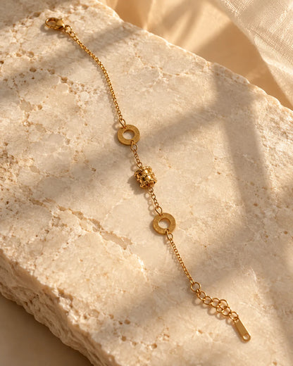 Gold Roman numeral drum bracelet on a sunlit stone block