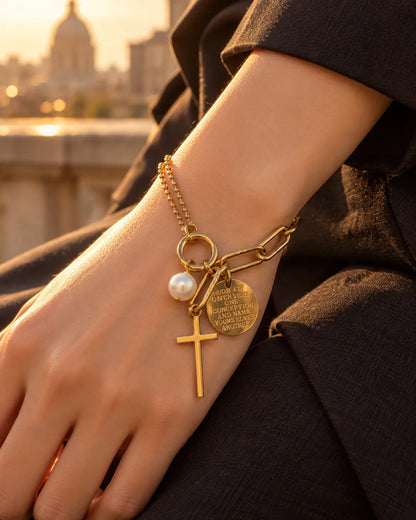 Wrist wearing the gold cross charm bracelet at sunset