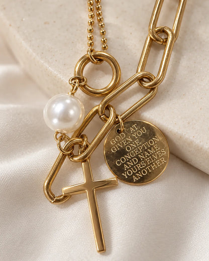 Close-up of the slim cross, engraved coin and pearl-look bead charms