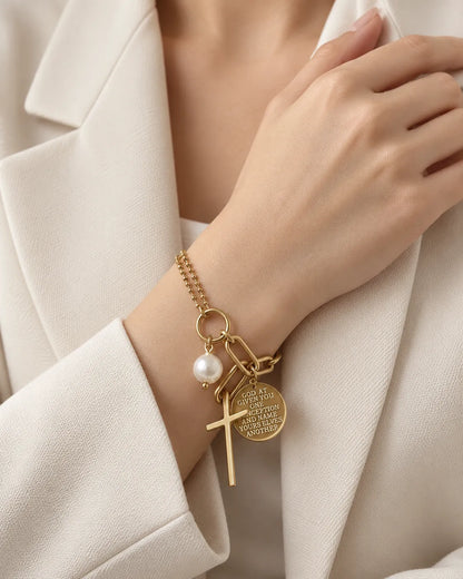 Wrist in a white blazer wearing the gold cross charm bracelet