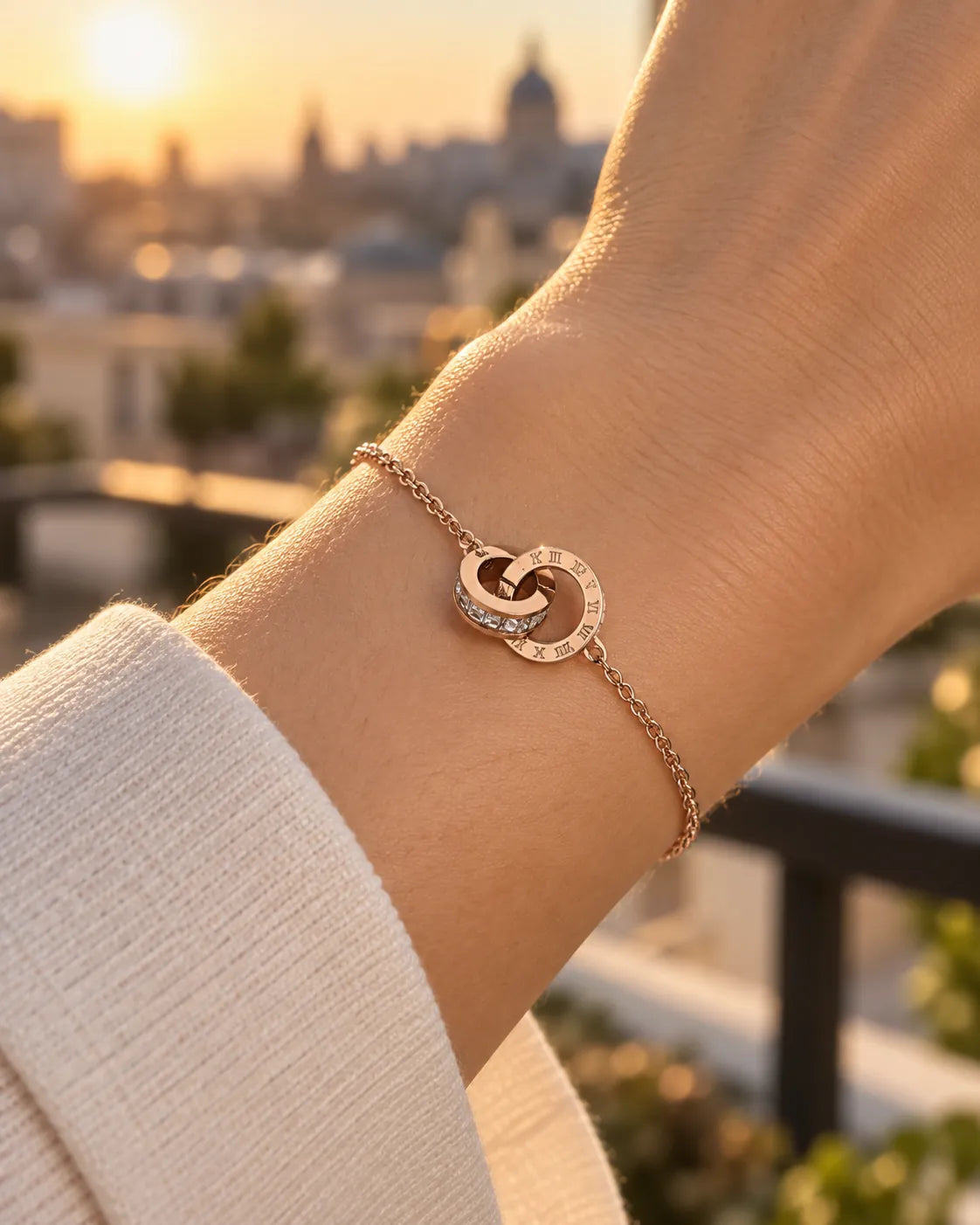Wrist wearing the rose gold circles bracelet at sunset over a city