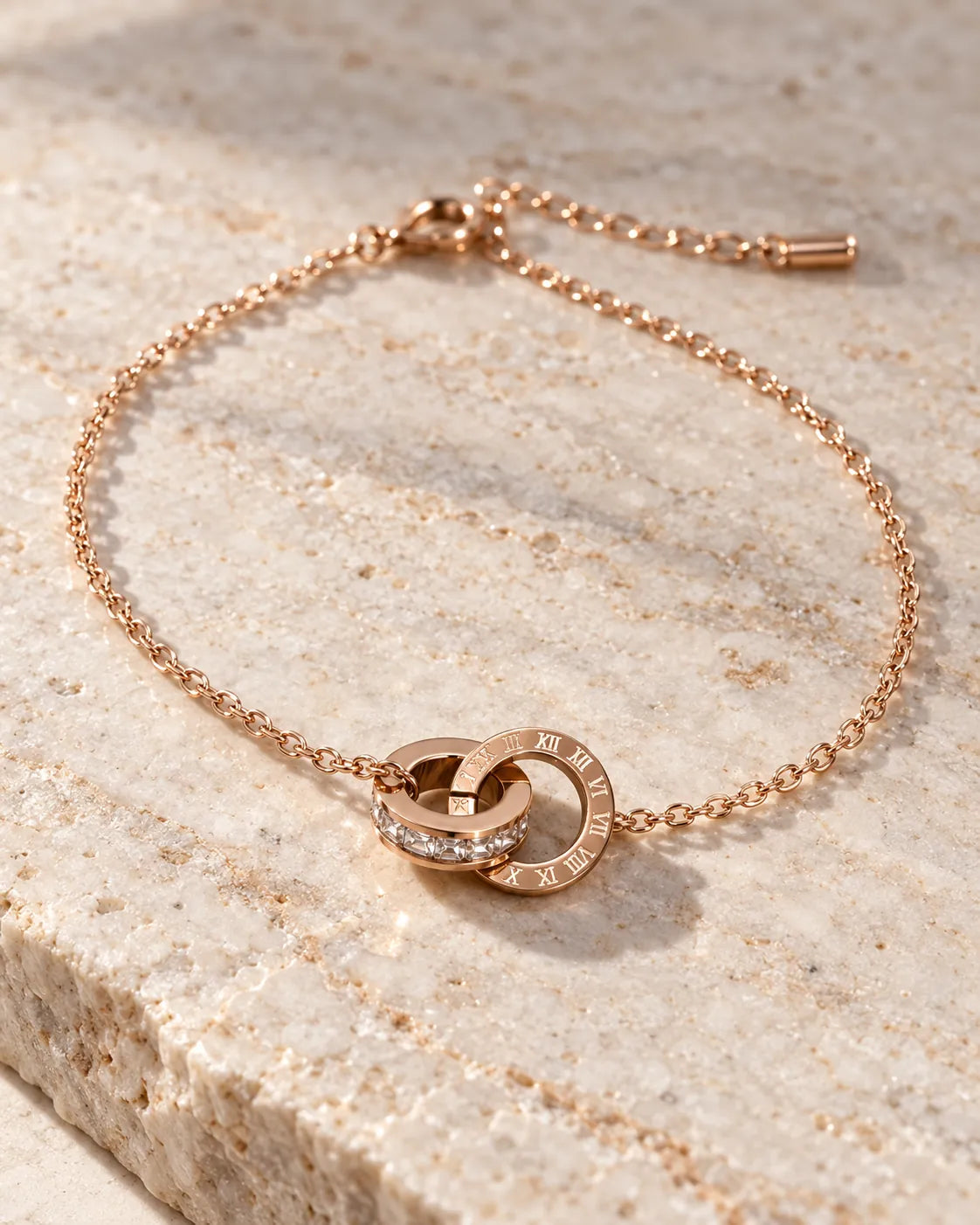 Rose gold interlocking circles bracelet on a stone slab