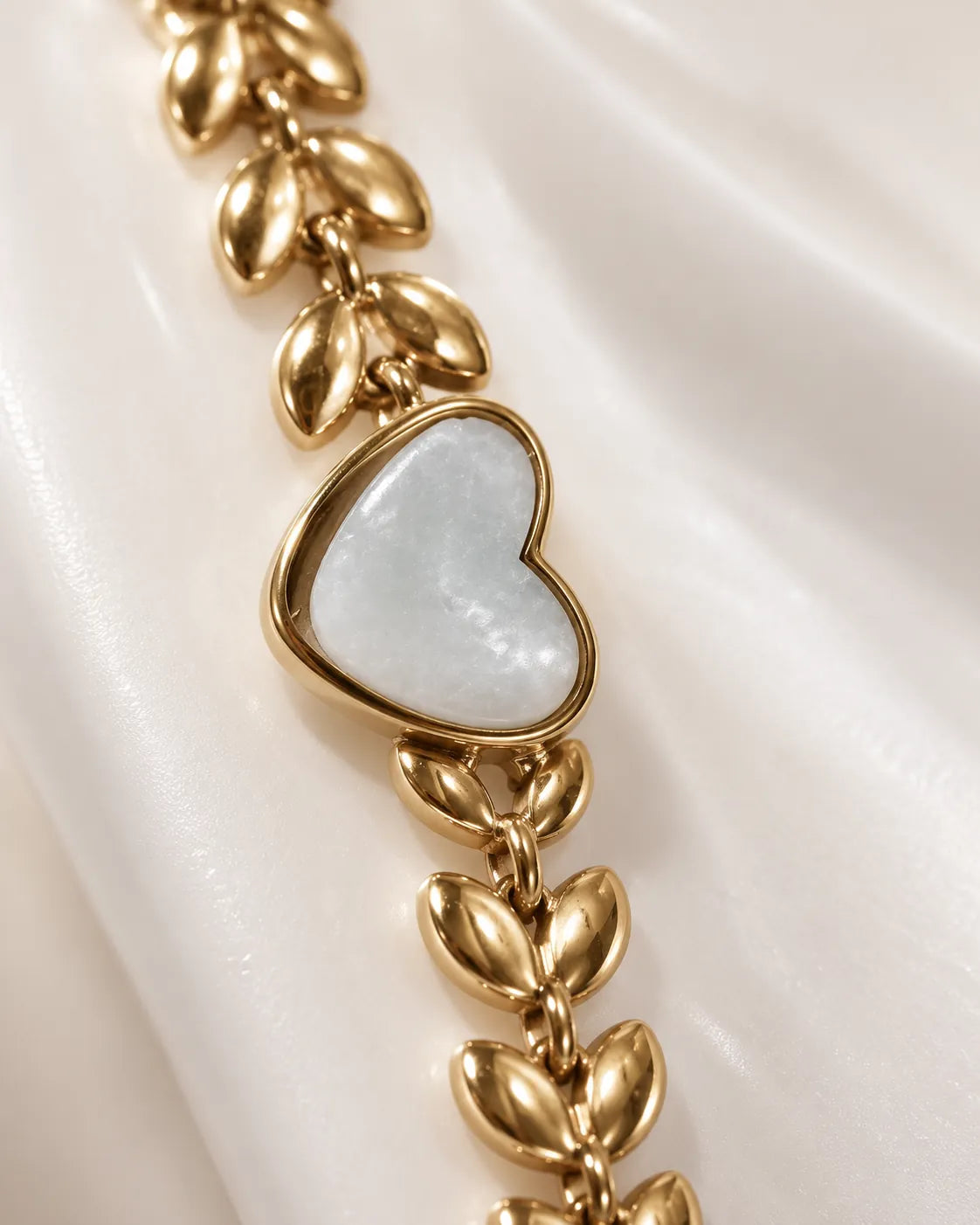 Close-up of the white heart in a gold frame between leaf-shaped links