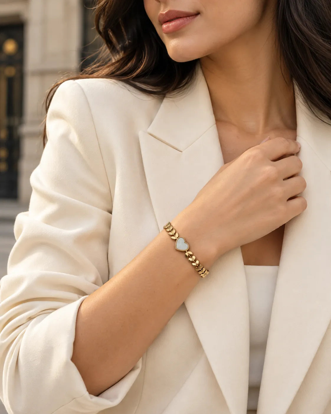 Model in a cream blazer wearing the gold leaf chain heart bracelet