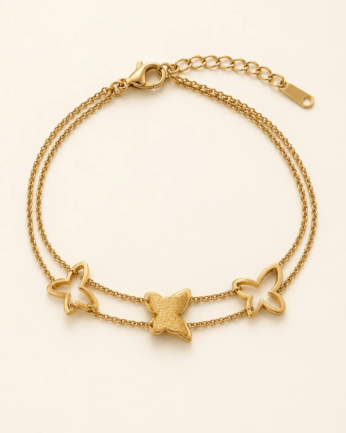 Gold double chain butterfly bracelet on a cream background