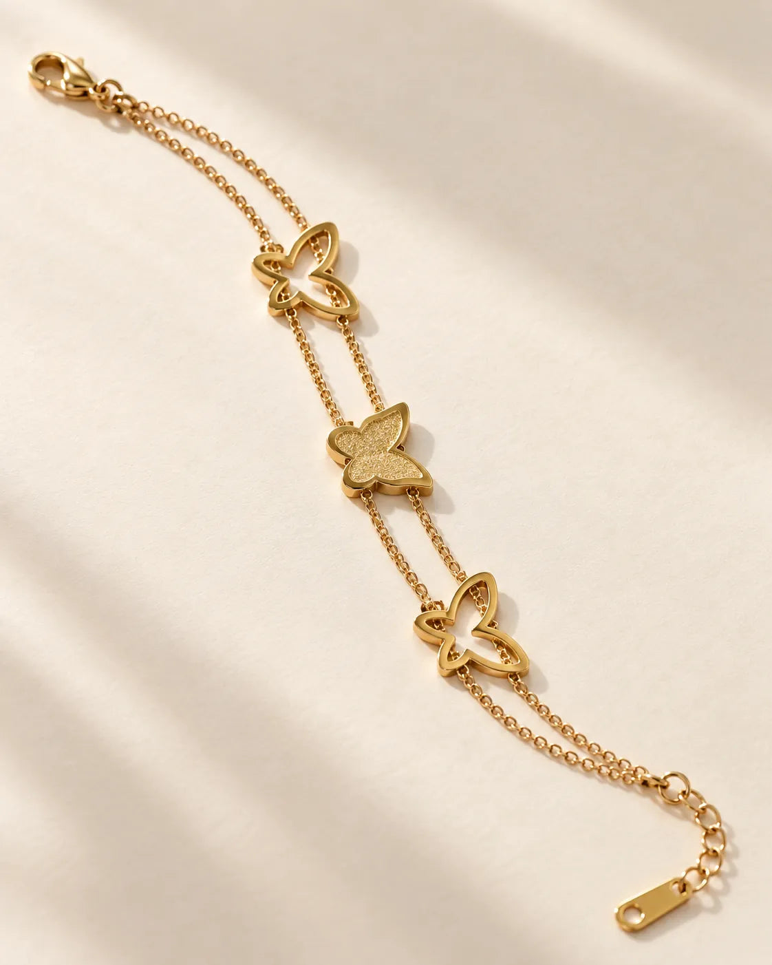 Gold butterfly bracelet laid diagonally on cream fabric