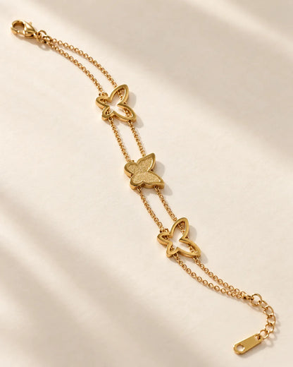 Gold butterfly bracelet laid diagonally on cream fabric