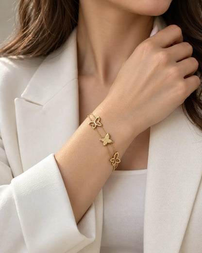 Model in a white blazer wearing the gold butterfly bracelet