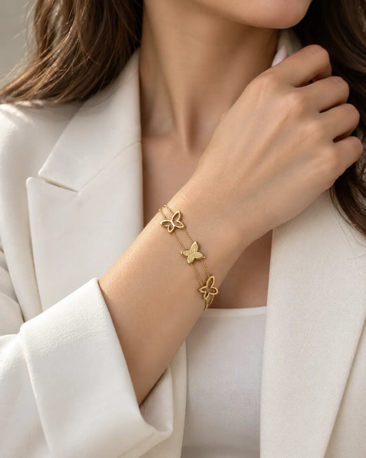 Model in a white blazer wearing the gold butterfly bracelet