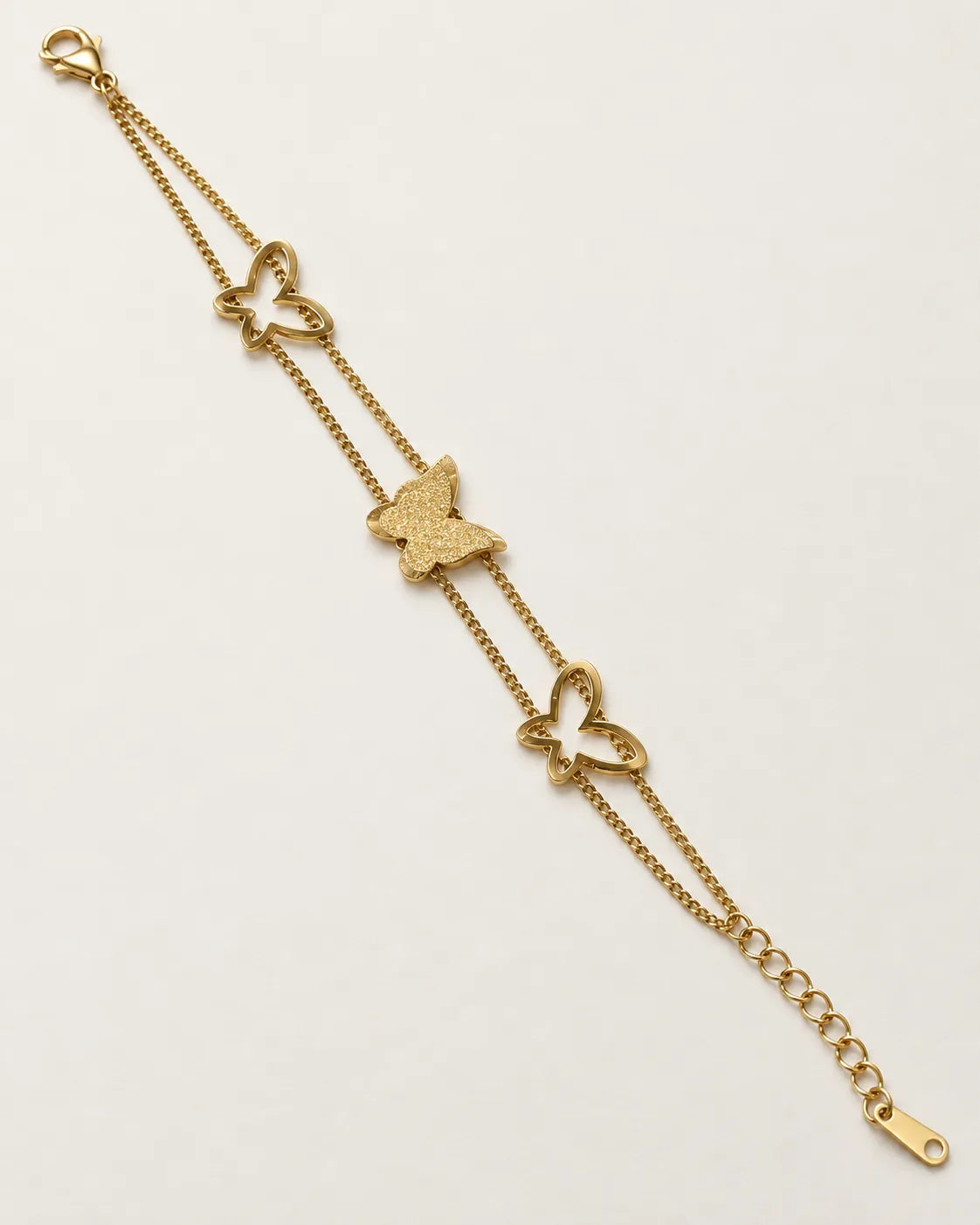 Gold double chain butterfly bracelet laid straight on a white background