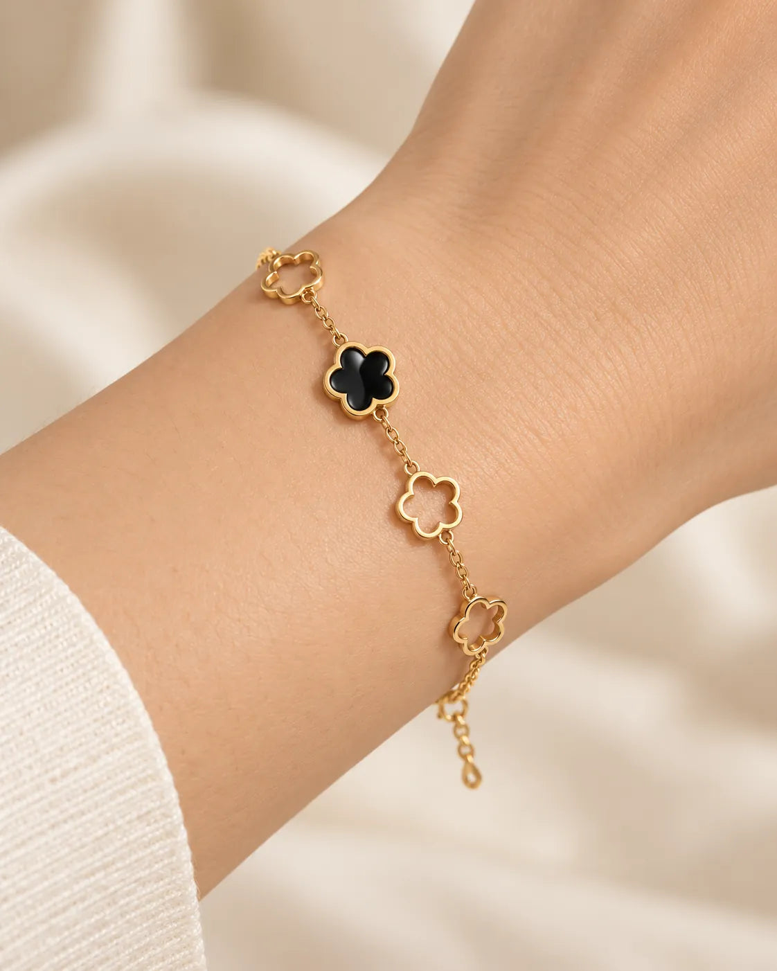 Wrist wearing the gold and black clover flower bracelet