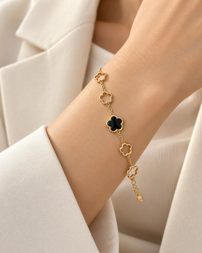 Wrist in a white blazer wearing the gold black clover bracelet