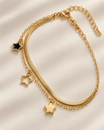 Gold snake chain and link chain star bracelet laid in a curve