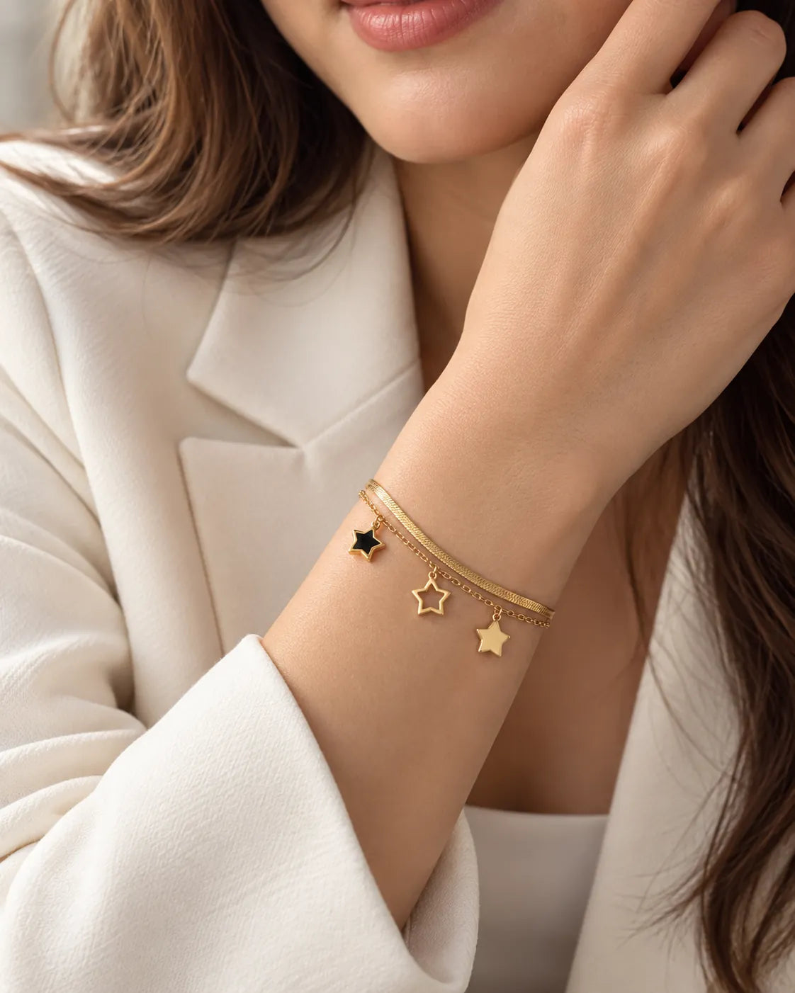 Model in a white blazer wearing the gold layered star bracelet