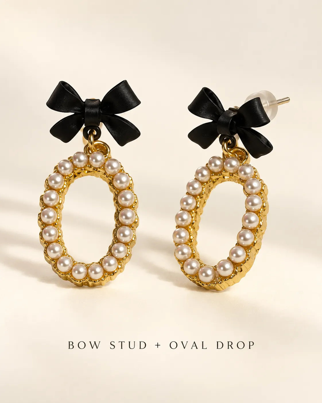 Bow stud and oval drop graphic of the black and gold-tone earrings