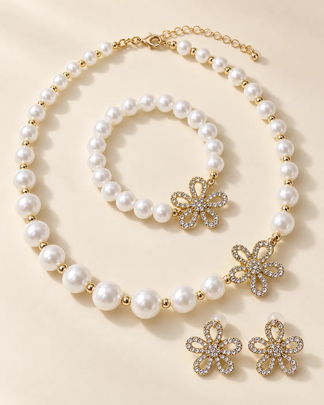 Gold flower pearl necklace, bracelet and crystal flower studs on cream