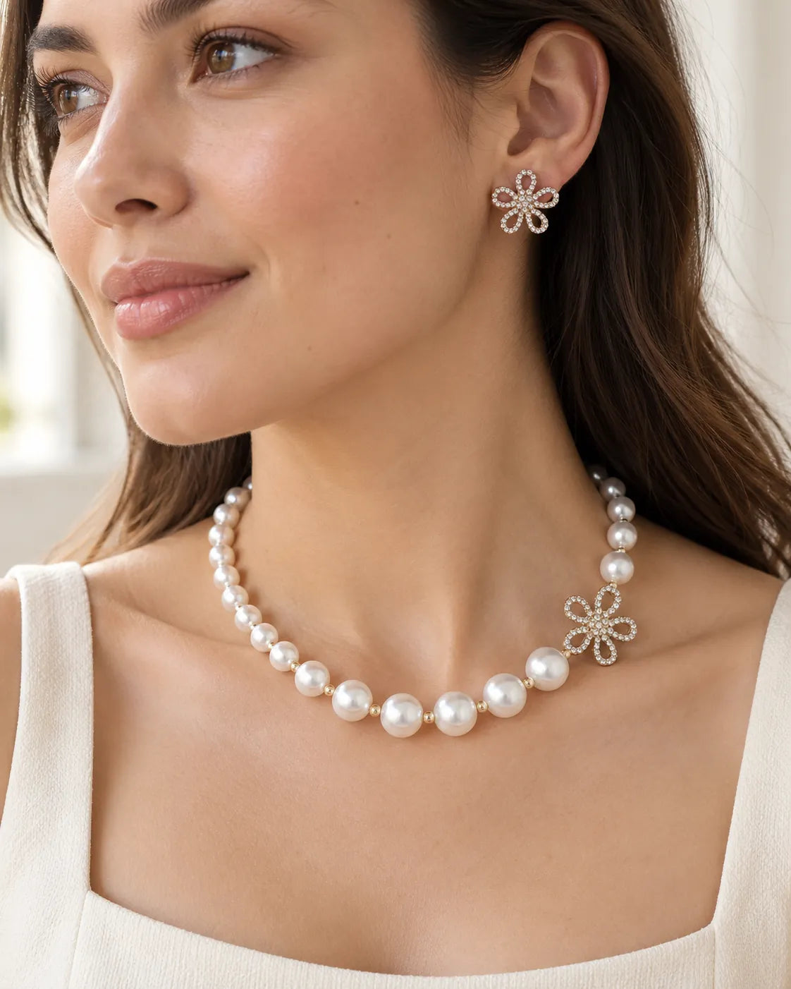 Model in a white square-neck top wearing the gold flower pearl necklace and studs