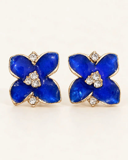 Pair of cobalt blue enamel camellia flower stud earrings on cream