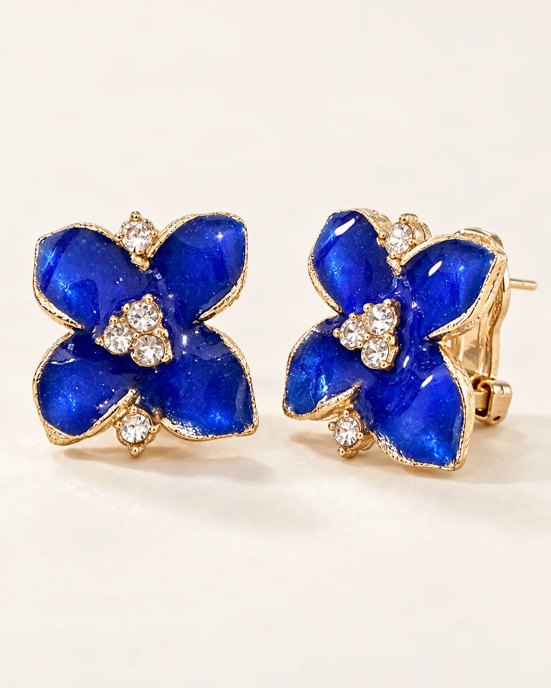 Angled pair of blue camellia studs showing the clip-style lever back